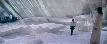 Movie still from “Superman II” (1980), directed by Richard Lester – A man in a white shirt is standing in the middle of a large pile of white rocks; Extreme Wide shot, High angle