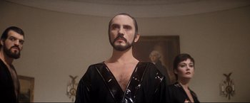 Movie still from “Superman II” (1980), directed by Richard Lester – A man with a beard wearing a black shirt; Medium shot, Low angle