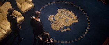 Movie still from “Superman II” (1980), directed by Richard Lester – Two people standing in front of an american flag; Wide shot, Overhead angle
