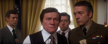 Movie still from “Superman II” (1980), directed by Richard Lester – A group of men standing next to each other in front of a window; Close Up shot, Over the shoulder angle