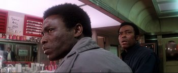 Movie still from “Superman II” (1980), directed by Richard Lester – Two men standing next to each other in front of a building; Close Up shot, Low angle