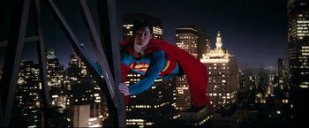 Movie still from “Superman II” (1980), directed by Richard Lester – A man dressed as superman is hanging from a pole; Wide shot, Low angle