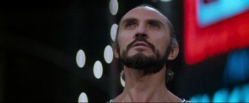 Movie still from “Superman II” (1980), directed by Richard Lester – A man with long hair and a goatee looking up; Close Up shot, Low angle