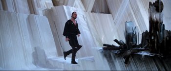 Movie still from “Superman II” (1980), directed by Richard Lester – A man in black shirt and black pants walking in front of a pile of rocks; Wide shot, Low angle