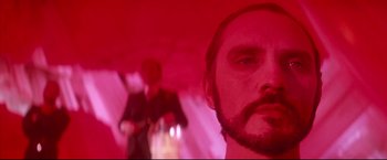 Movie still from “Superman II” (1980), directed by Richard Lester – A man with a beard and a man in a suit in the background; Close Up shot, Low angle