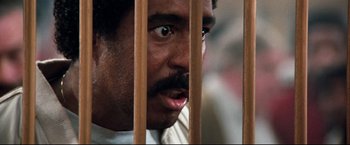 Movie still from “Superman III” (1983), directed by Richard Lester – A person behind a wooden fence; Close Up shot, High angle