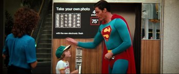 Movie still from “Superman III” (1983), directed by Richard Lester – A man in a superman costume and a little girl; Medium shot, Over the shoulder angle