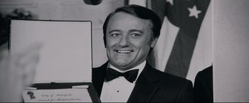 Movie still from “Superman III” (1983), directed by Richard Lester – A black and white photo of a man in a tuxedo; Close Up shot, Low angle