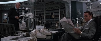 Movie still from “Superman III” (1983), directed by Richard Lester – A room filled with lots of bookshelves and a desk; Medium shot, Over the shoulder angle