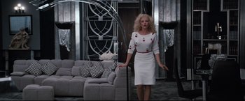 Movie still from “Superman III” (1983), directed by Richard Lester – A woman standing in front of a couch in a room; Wide shot, Low angle