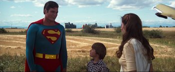 Movie still from “Superman III” (1983), directed by Richard Lester – A man in a superman costume standing next to two other people; Medium shot, Over the shoulder angle