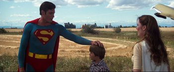 Movie still from “Superman III” (1983), directed by Richard Lester – A man in a superman costume standing next to a boy in a plaid shirt; Medium shot, Over the shoulder angle