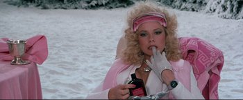 Movie still from “Superman III” (1983), directed by Richard Lester – A woman in a pink and white outfit sitting in the snow; Medium shot, Over the shoulder angle