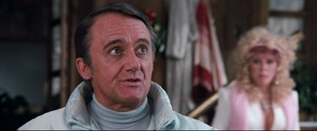 Movie still from “Superman III” (1983), directed by Richard Lester – An older man wearing a white jacket looking at the camera; Close Up shot, Low angle