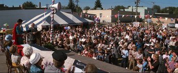 Movie still from “Superman III” (1983), directed by Richard Lester – A crowd of people sitting on a stage in front of an audience; Wide shot, High angle