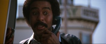 Movie still from “Superman III” (1983), directed by Richard Lester – A man holding a phone up to his ear; Close Up shot, Low angle