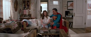 Movie still from “Superman III” (1983), directed by Richard Lester – A man and a woman sitting on top of a white couch; Wide shot, Over the shoulder angle