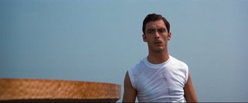 Movie still from “Superman III” (1983), directed by Richard Lester – A man in a white shirt is standing in front of a bowl; Close Up shot, Low angle