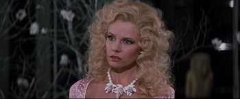 Movie still from “Superman III” (1983), directed by Richard Lester – A woman in a pink and white dress with a white necklace; Close Up shot, Over the shoulder angle