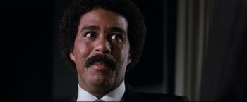 Movie still from “Superman III” (1983), directed by Richard Lester – Close up of a man in a suit and tie looking up; Close Up shot, Low angle