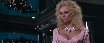 Movie still from “Superman III” (1983), directed by Richard Lester – A woman with blonde hair and a pink polka dot dress; Close Up shot, Low angle