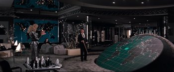 Movie still from “Superman III” (1983), directed by Richard Lester – A man in a suit and tie standing in front of a room; Wide shot, High angle