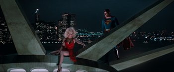 Movie still from “Superman III” (1983), directed by Richard Lester – A man and a woman dressed as superman and a woman dressed as marilyn monroe in front of a city skyline at night; Wide shot, Low angle