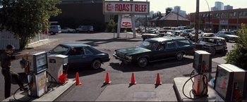 Movie still from “Superman III” (1983), directed by Richard Lester – A group of cars driving down a street next to orange cones; Extreme Wide shot, High angle