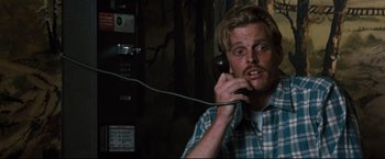 Movie still from “Superman III” (1983), directed by Richard Lester – A man talking on a phone while sitting down; Close Up shot, High angle