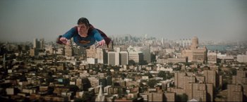 Movie still from “Superman III” (1983), directed by Richard Lester – A man flying through the air over a city; Wide shot, Low angle