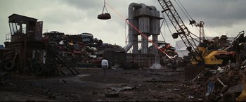 Movie still from “Superman III” (1983), directed by Richard Lester – A man standing next to a pile of trash; Extreme Wide shot, High angle