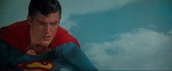 Movie still from “Superman III” (1983), directed by Richard Lester – A man in a superman costume standing in front of the sky; Close Up shot, Over the shoulder angle