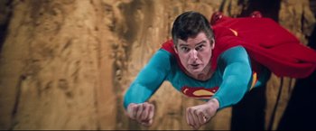 Movie still from “Superman III” (1983), directed by Richard Lester – A man flying through the air while wearing a superman costume; Medium shot, Low angle