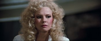 Movie still from “Superman III” (1983), directed by Richard Lester – A person with long blonde hair; Close Up shot, Over the shoulder angle