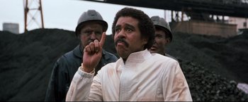 Movie still from “Superman III” (1983), directed by Richard Lester – A man with a beard is pointing up; Close Up shot, Low angle