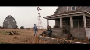 Movie still from “Superman IV: The Quest for Peace” (1987), directed by Sidney J. Furie – A man standing in front of an old farm house; Extreme Wide shot, Over the shoulder angle