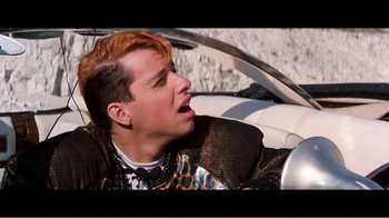 Movie still from “Superman IV: The Quest for Peace” (1987), directed by Sidney J. Furie – A young man with red hair is sitting in the driver's seat of a car; Close Up shot, Over the shoulder angle