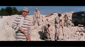 Movie still from “Superman IV: The Quest for Peace” (1987), directed by Sidney J. Furie – A group of men in prison uniforms working on a pile of rocks; Wide shot, High angle