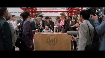 Movie still from “Superman IV: The Quest for Peace” (1987), directed by Sidney J. Furie – A group of people standing around a wooden podium with microphones; Wide shot, High angle