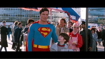 Movie still from “Superman IV: The Quest for Peace” (1987), directed by Sidney J. Furie – A man in a superman costume standing next to a child; Medium shot, Over the shoulder angle