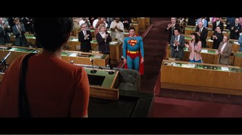 Movie still from “Superman IV: The Quest for Peace” (1987), directed by Sidney J. Furie – A man in a superman suit stands in front of a group of people; Wide shot, High angle
