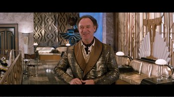 Movie still from “Superman IV: The Quest for Peace” (1987), directed by Sidney J. Furie – A man wearing a suit and tie standing in front of a counter; Medium shot, High angle