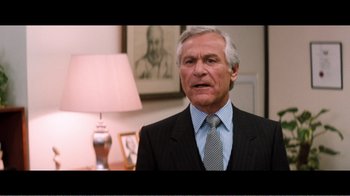 Movie still from “Superman IV: The Quest for Peace” (1987), directed by Sidney J. Furie – An older man wearing a suit and tie in front of a lamp; Medium shot, Low angle
