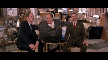 Movie still from “Superman IV: The Quest for Peace” (1987), directed by Sidney J. Furie – A group of men sitting around a table together; Wide shot, Low angle