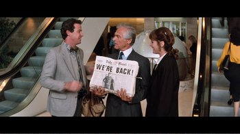 Movie still from “Superman IV: The Quest for Peace” (1987), directed by Sidney J. Furie – A man and two women are holding a newspaper; Medium shot, Low angle