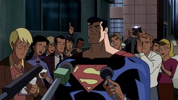 Movie still from “Superman: Doomsday” (2007), directed by Bruce Timm – A man in a superman costume is being interviewed; Medium shot, Over the shoulder angle