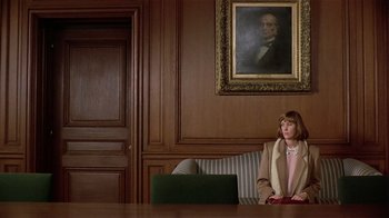 Movie still from “Suspect” (1987), directed by Peter Yates – A woman sitting in front of a laptop computer in front of a portrait of abraham lincoln on the wall; Wide shot, Low angle