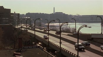 Movie still from “Suspect” (1987), directed by Peter Yates – Cars driving on a highway near a body of water; Extreme Wide shot, High angle