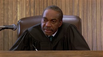 Movie still from “Suspect” (1987), directed by Peter Yates – A judge sitting at a table in a courtroom; Close Up shot, High angle