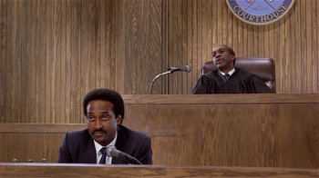 Movie still from “Suspect” (1987), directed by Peter Yates – Two men sitting in front of a microphone in front of a judge; Medium shot, Low angle